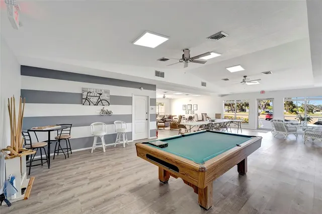 a living room with furniture pool table and wooden floor