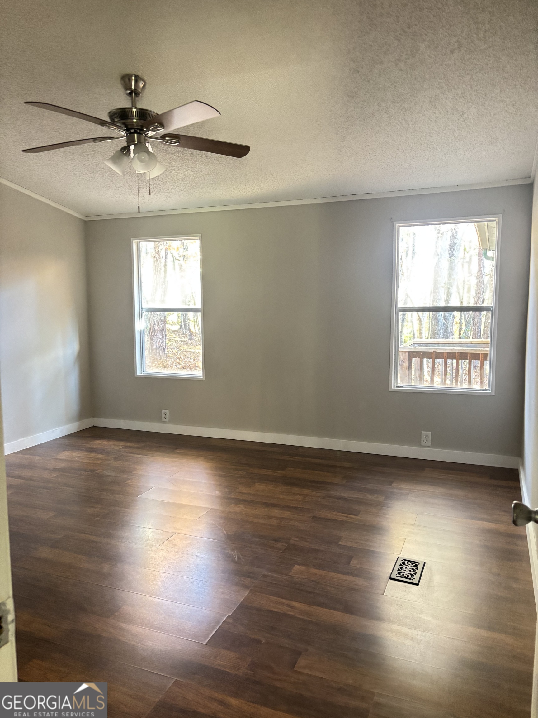 358 Whippoorwill Road Monticello, GA 31064 - Photo 14 of 20 an empty room with wooden floor chandelier fan and windows
