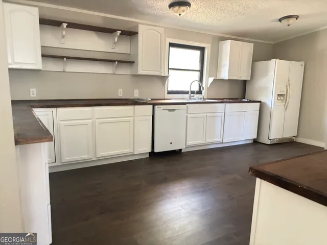 a kitchen with stainless steel appliances granite countertop a refrigerator sink and white cabinets