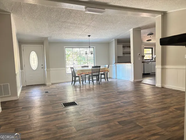 a view of a dining room and livingroom with furniture wooden floor a chandelier