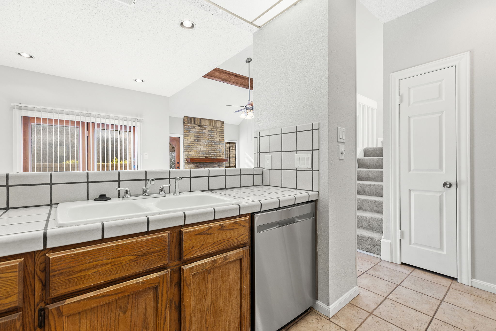 10819 Crown Colony Drive, Unit 11 Austin, TX 78747 - Photo 16 of 40 Warm wood cabinetry lines the space, paired with tiled countertops that offer generous prep room and an easy, practical flow for everyday cooking.