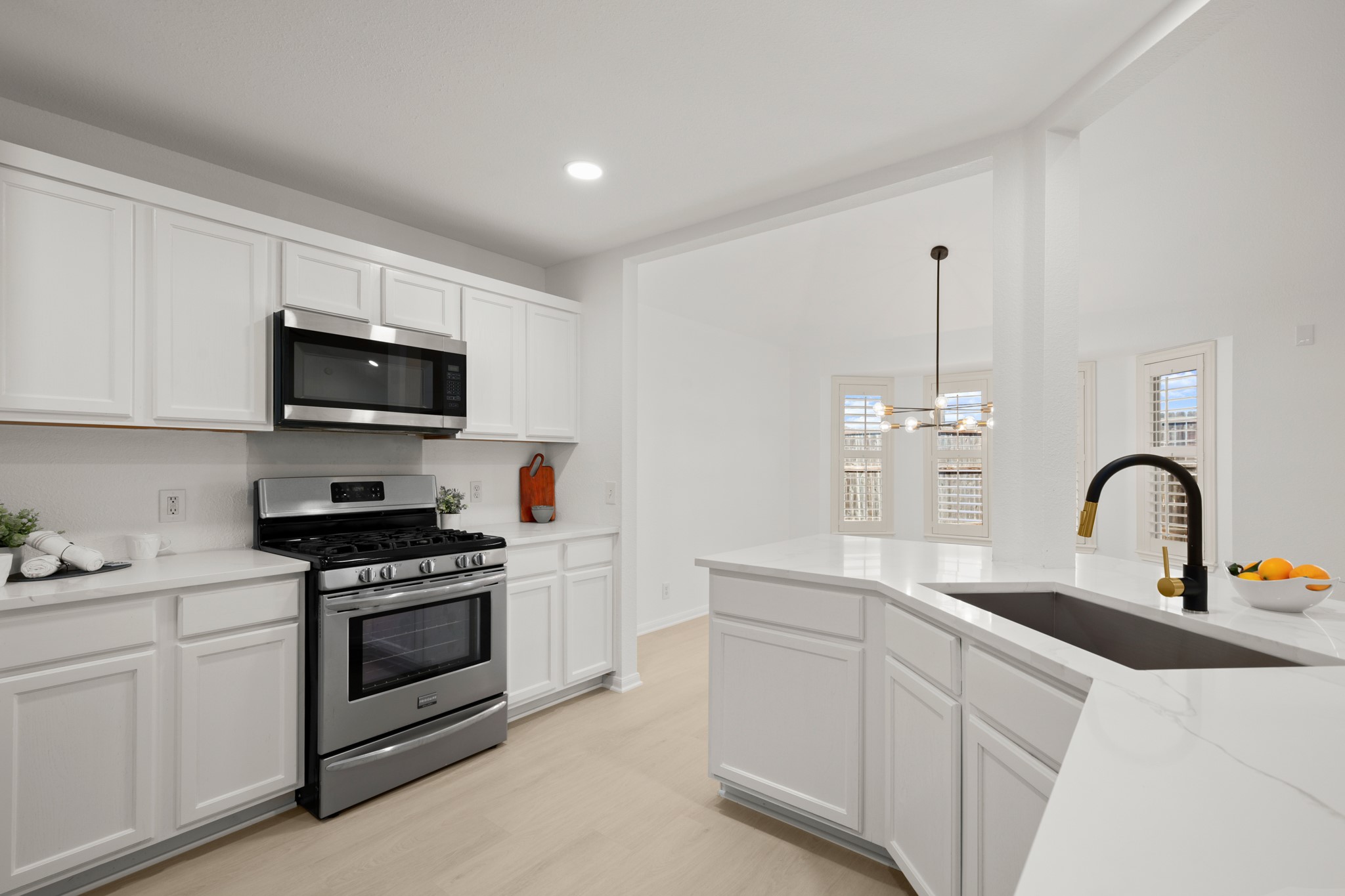 310 Bailey Loop Kyle, TX 78640 - Photo 15 of 30 Kitchen with stainless steel appliances, white cabinetry, hanging light fixtures, light stone countertops, and light wood-style floors