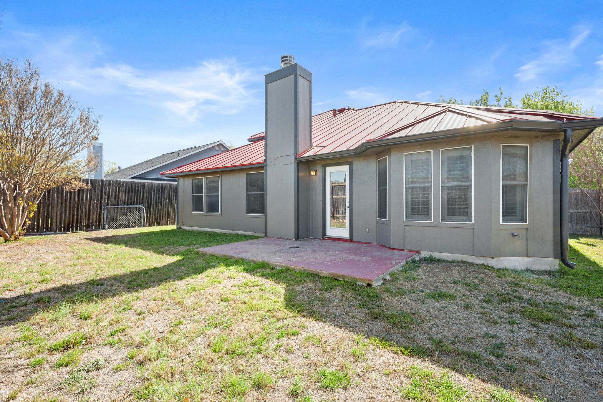 310 Bailey Loop Kyle, TX 78640 - Photo 27 of 30 Back of property with a patio, a fenced backyard, a chimney, and a metal roof