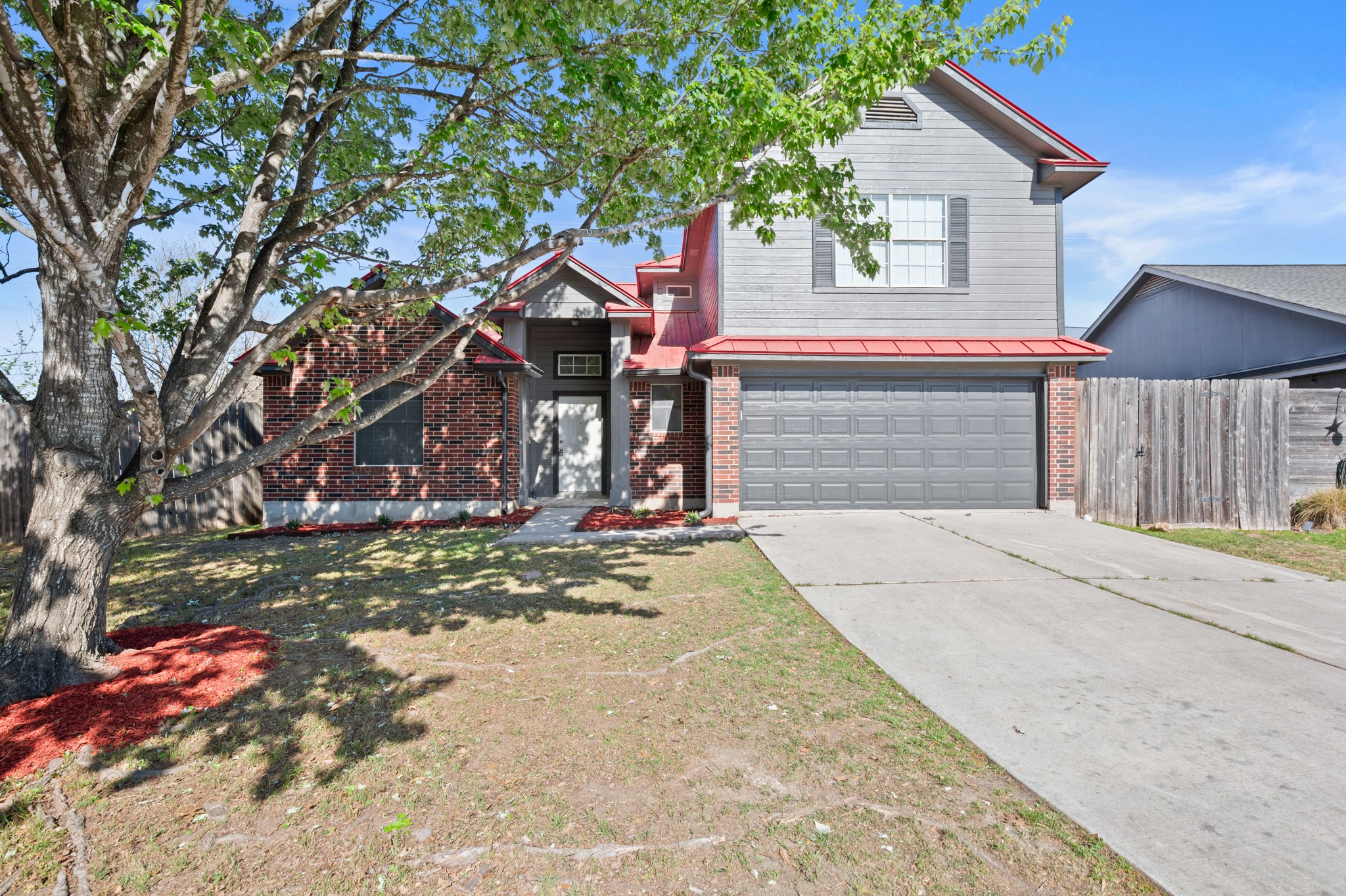310 Bailey Loop Kyle, TX 78640 - Photo 3 of 30 View of front of house featuring driveway, an attached garage, brick siding, and a metal roof