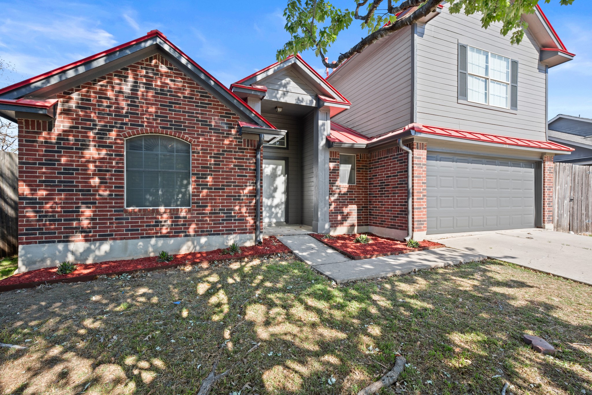 310 Bailey Loop Kyle, TX 78640 - Photo 4 of 30 Traditional-style house featuring a garage, concrete driveway, brick siding, and a metal roof