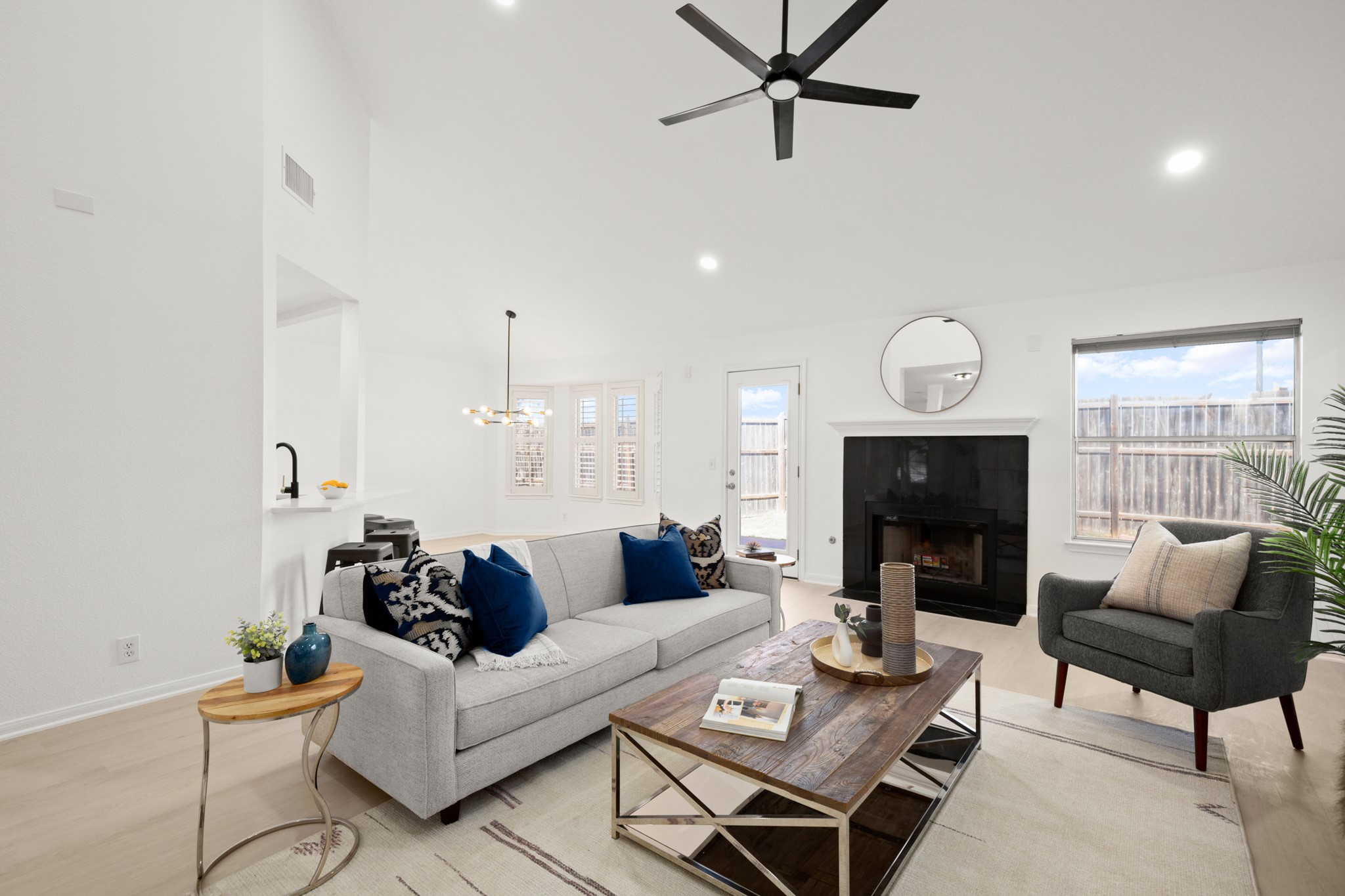 310 Bailey Loop Kyle, TX 78640 - Photo 10 of 30 Living room featuring a tiled fireplace, a ceiling fan, light wood-type flooring, vaulted ceiling, and hanging lights