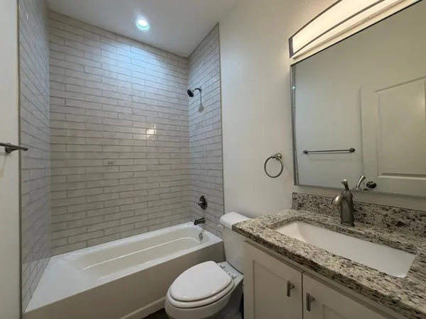 a bathroom with a granite countertop sink toilet and shower