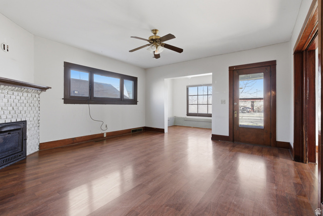 869 West Center Street Provo, UT 84601 - Photo 7 of 32 Unfurnished living room with dark wood-type flooring, a ceiling fan, and a brick fireplace