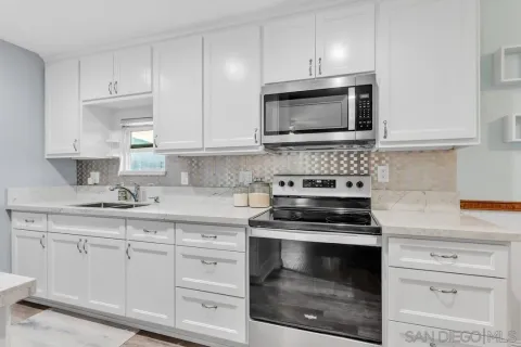 a kitchen with white cabinets and appliances
