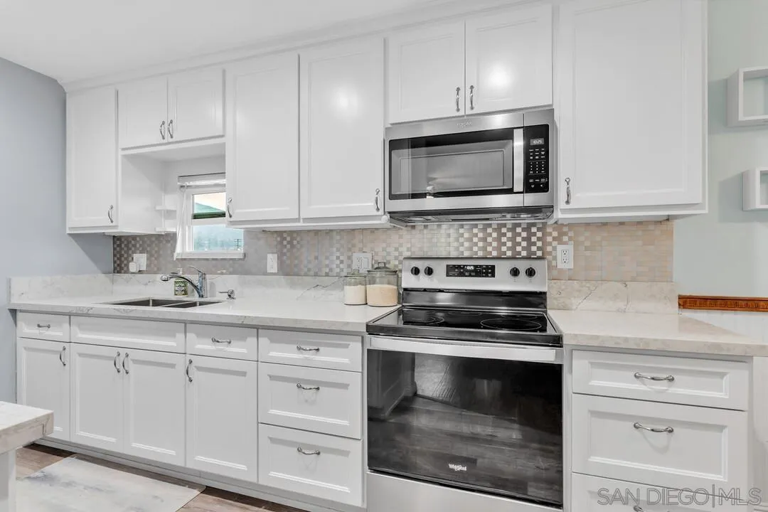 a kitchen with white cabinets and appliances