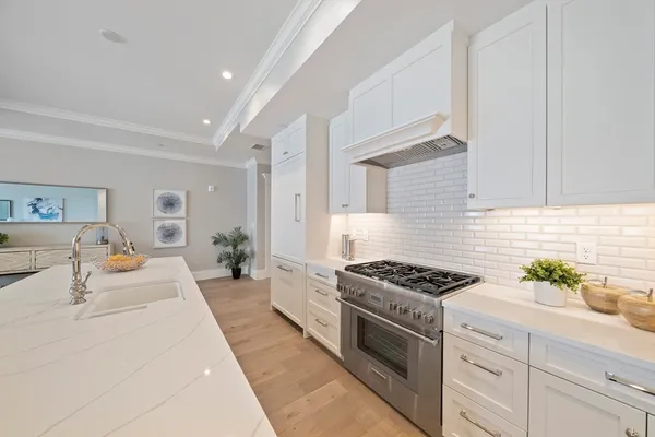 a kitchen with stainless steel appliances kitchen island granite countertop a stove a sink and white cabinets