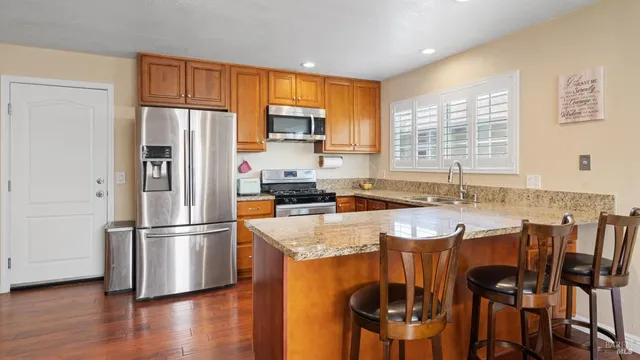a kitchen with stainless steel appliances granite countertop a refrigerator a stove a sink a dining table and chairs