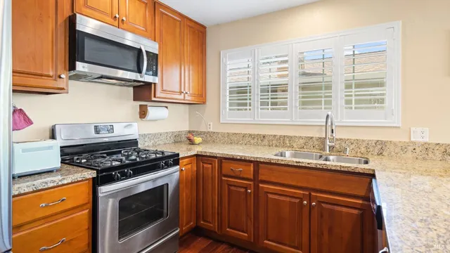a living room with stainless steel appliances granite countertop furniture wooden floor and a kitchen view