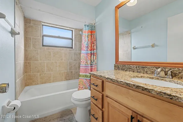 a bathroom with a granite countertop bathtub sink vanity mirror and toilet