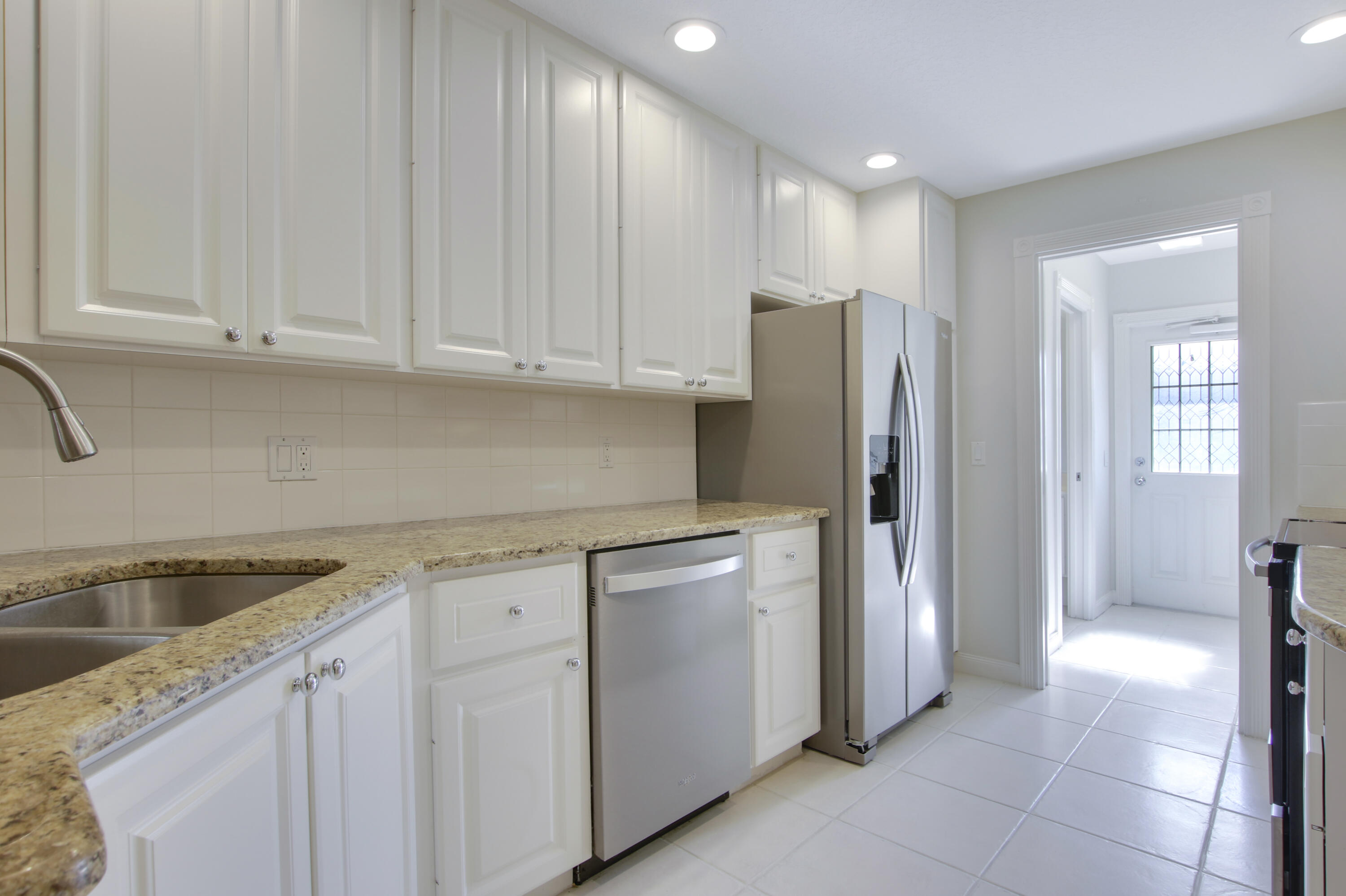 3057 East Community Drive Jupiter, FL 33458 - Photo 15 of 23 a kitchen with stainless steel appliances granite countertop white cabinets and refrigerator