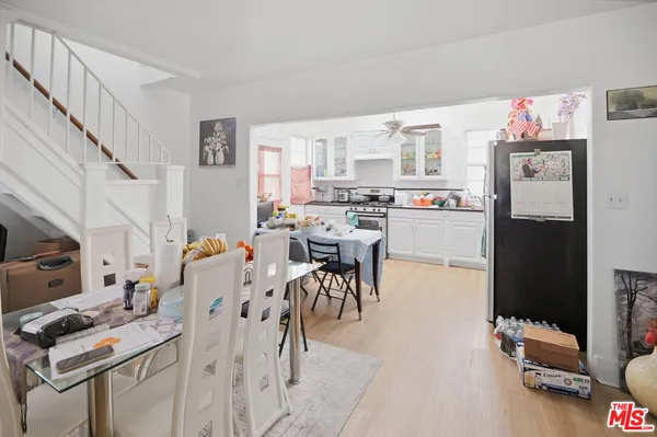 a kitchen with stainless steel appliances a refrigerator a stove a sink dishwasher and a dining table with wooden floor