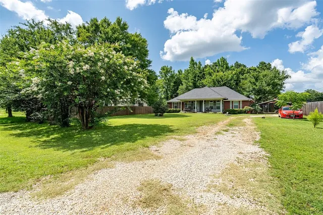 a view of house with garden space and trees in the background