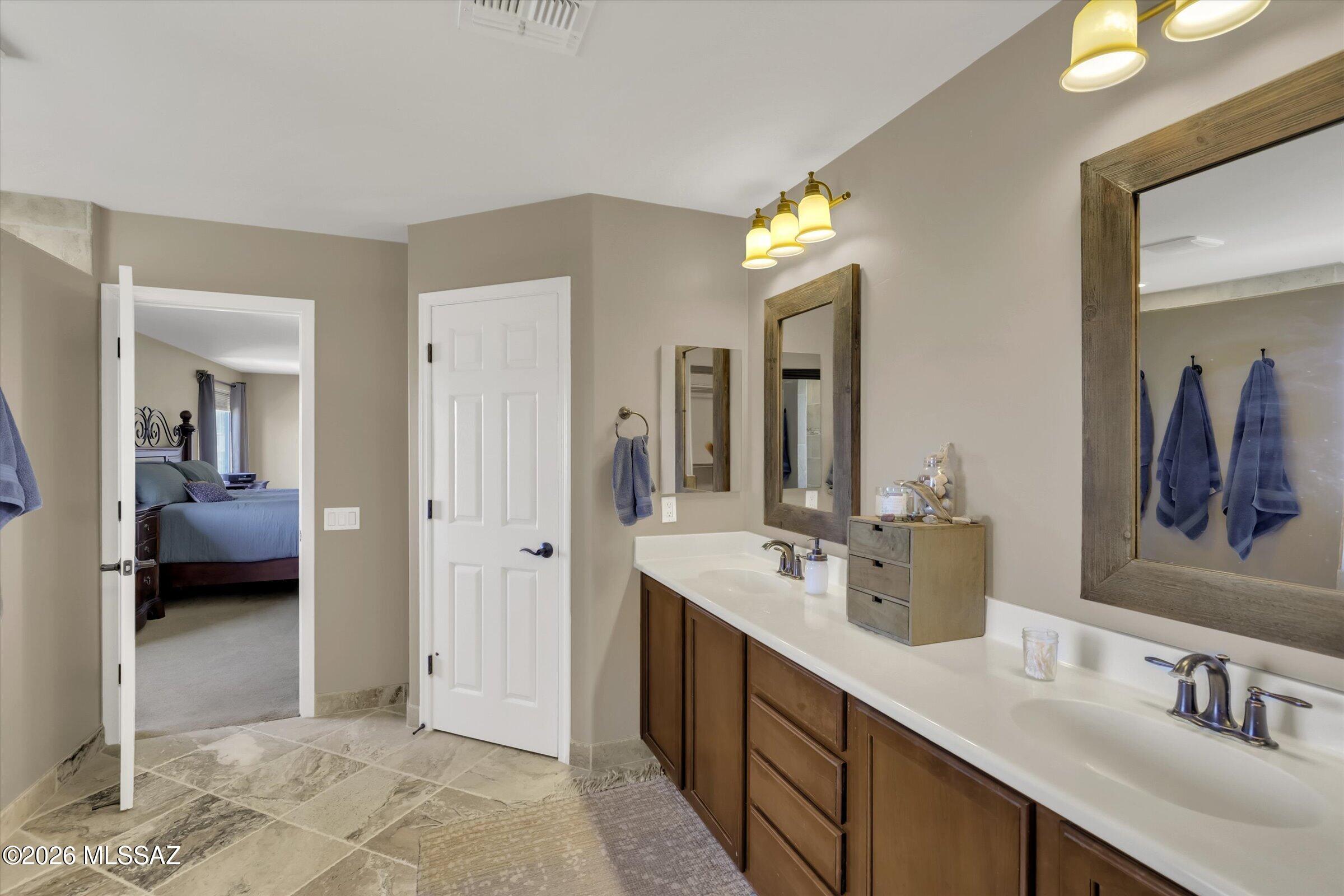 6095 South Jakemp Trail Tucson, AZ 85747 - Photo 29 of 52 a en suite bathroom with a double vanity sink and a mirror