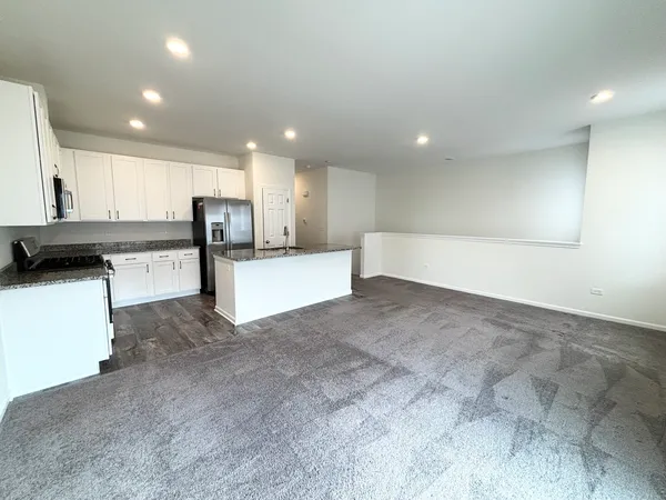 a view of a kitchen with refrigerator and white cabinets