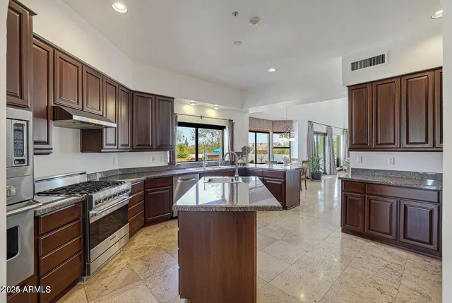 a kitchen with granite countertop a sink a counter top space appliances and cabinets