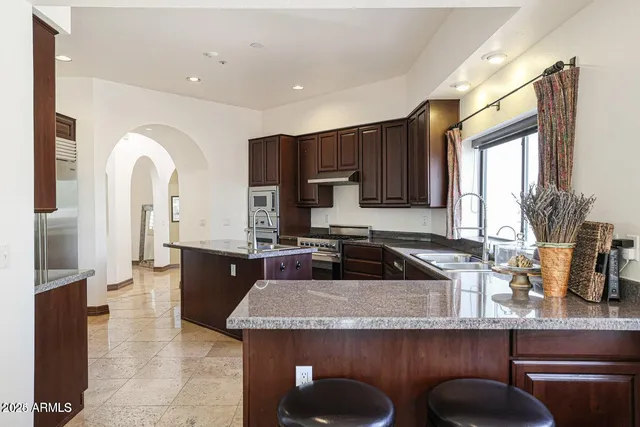 a kitchen with kitchen island granite countertop a sink stove and cabinets