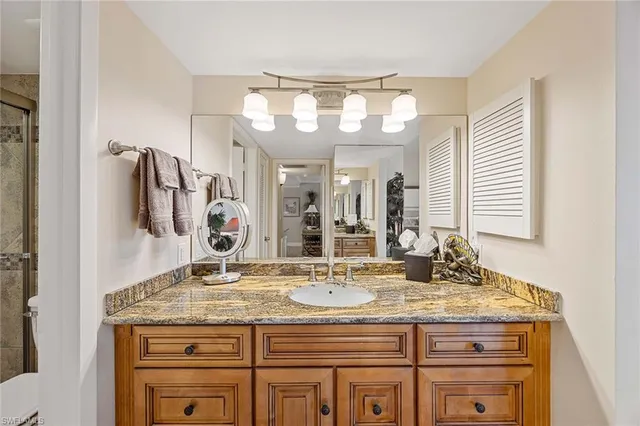a bathroom with a granite countertop sink a large mirror and a shower