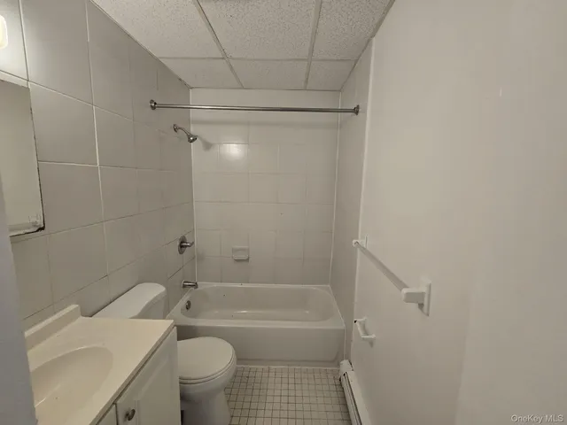 a bathroom with a granite countertop bathtub shower sink vanity and toilet