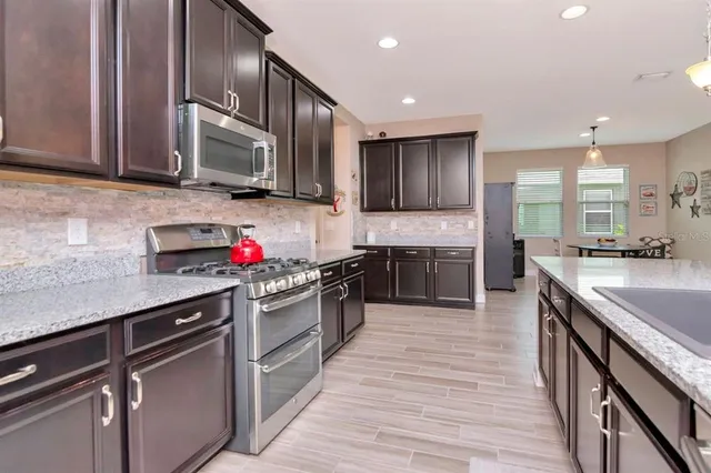a kitchen with kitchen island granite countertop a stove microwave and refrigerator