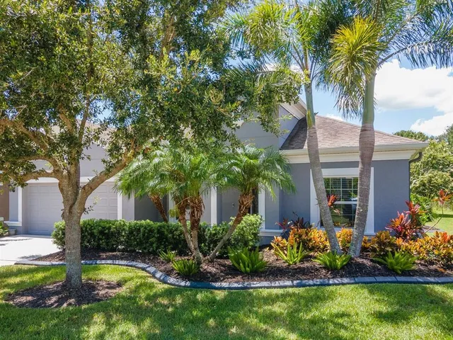 a view of a house with a yard and palm trees