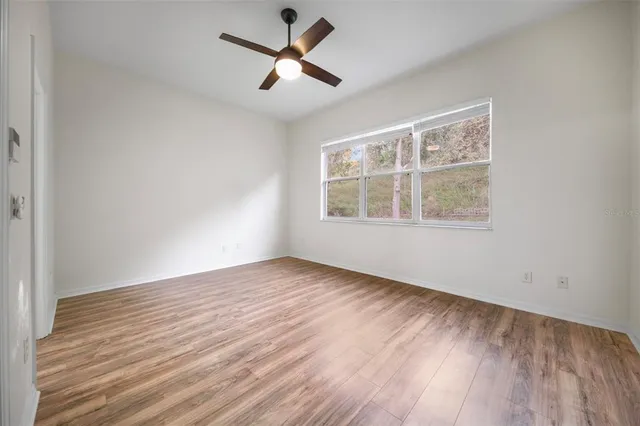 a view of empty room with wooden floor and ceiling fan