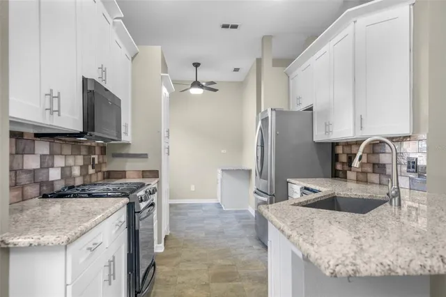 a kitchen with stainless steel appliances granite countertop a sink a stove and a refrigerator