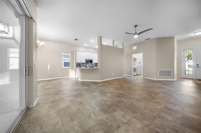 an empty room with a kitchen and windows