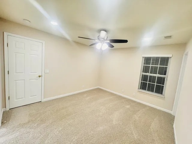an empty room with windows and ceiling fan