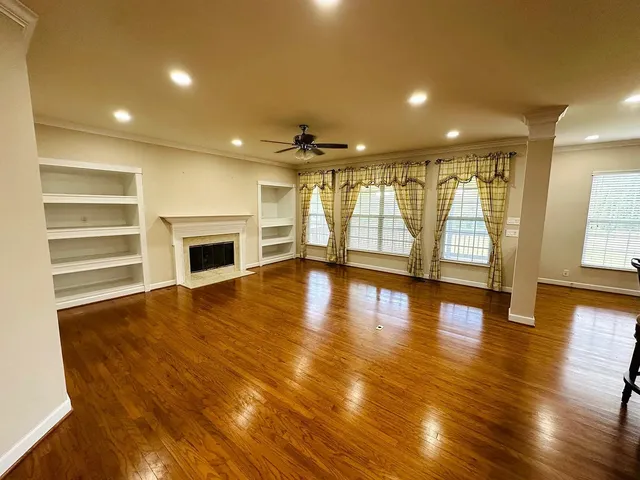 a view of an empty room with wooden floor and a fireplace