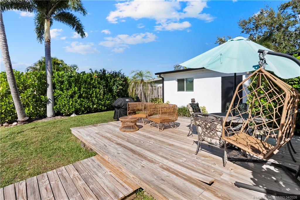 2446-2456 Southwest Hideaway Lane Stuart, FL 34994 - Photo 27 of 42 a view of a patio with table and chairs with wooden floor and fence