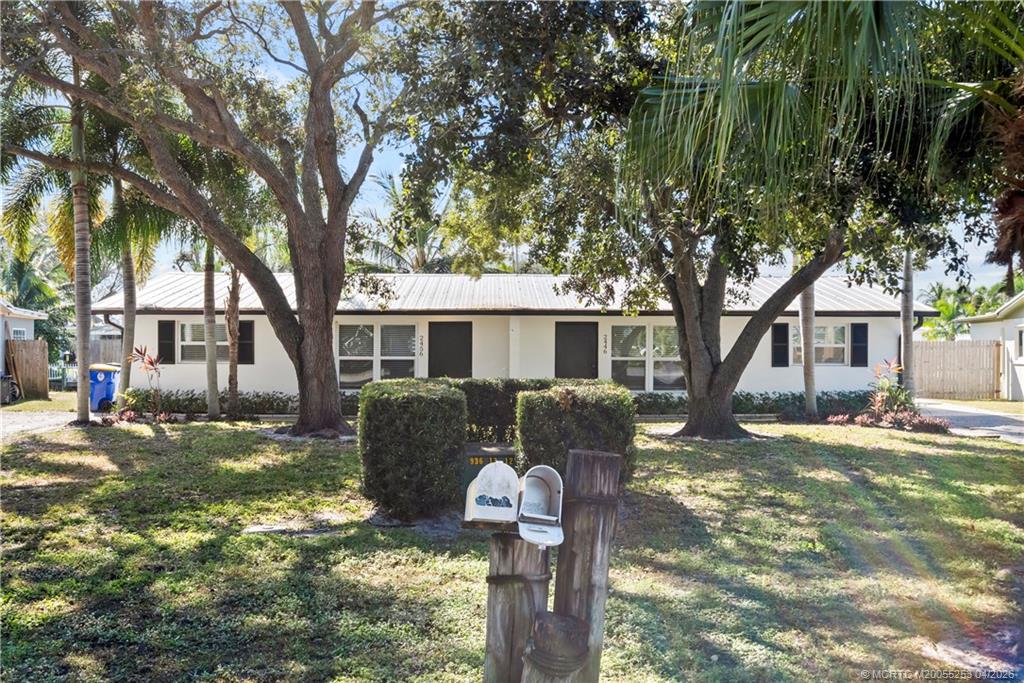 2446-2456 Southwest Hideaway Lane Stuart, FL 34994 - Photo 32 of 42 a front view of a house with a tree and yard