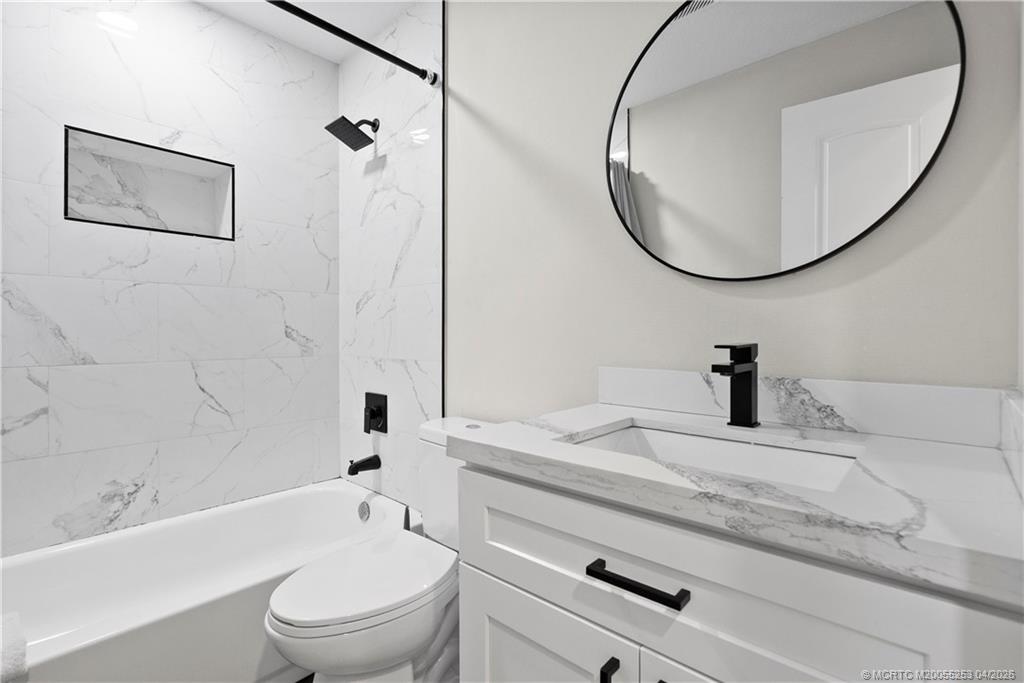 2446-2456 Southwest Hideaway Lane Stuart, FL 34994 - Photo 8 of 42 a bathroom with a granite countertop toilet a sink and a mirror