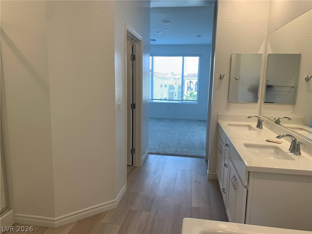 2555 Hampton Road, Unit 7109 Henderson, NV 89052 - Photo 22 of 34 Dual vanities and wood flooring grace this functional primary bathroom.
