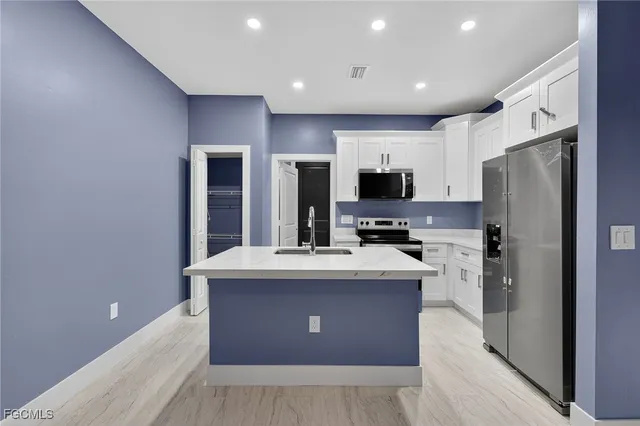 a kitchen with kitchen island a counter top space stainless steel appliances and cabinets