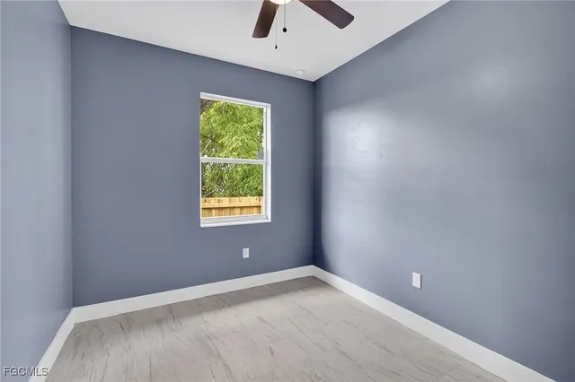 an empty room with a window and a ceiling fan