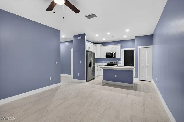 a large kitchen with stainless steel appliances kitchen island granite countertop a refrigerator and a sink