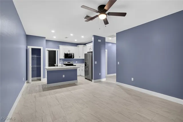 a large kitchen with stainless steel appliances kitchen island granite countertop a refrigerator and a sink