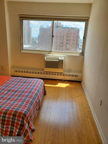 a spacious bedroom with a bed and wooden floor