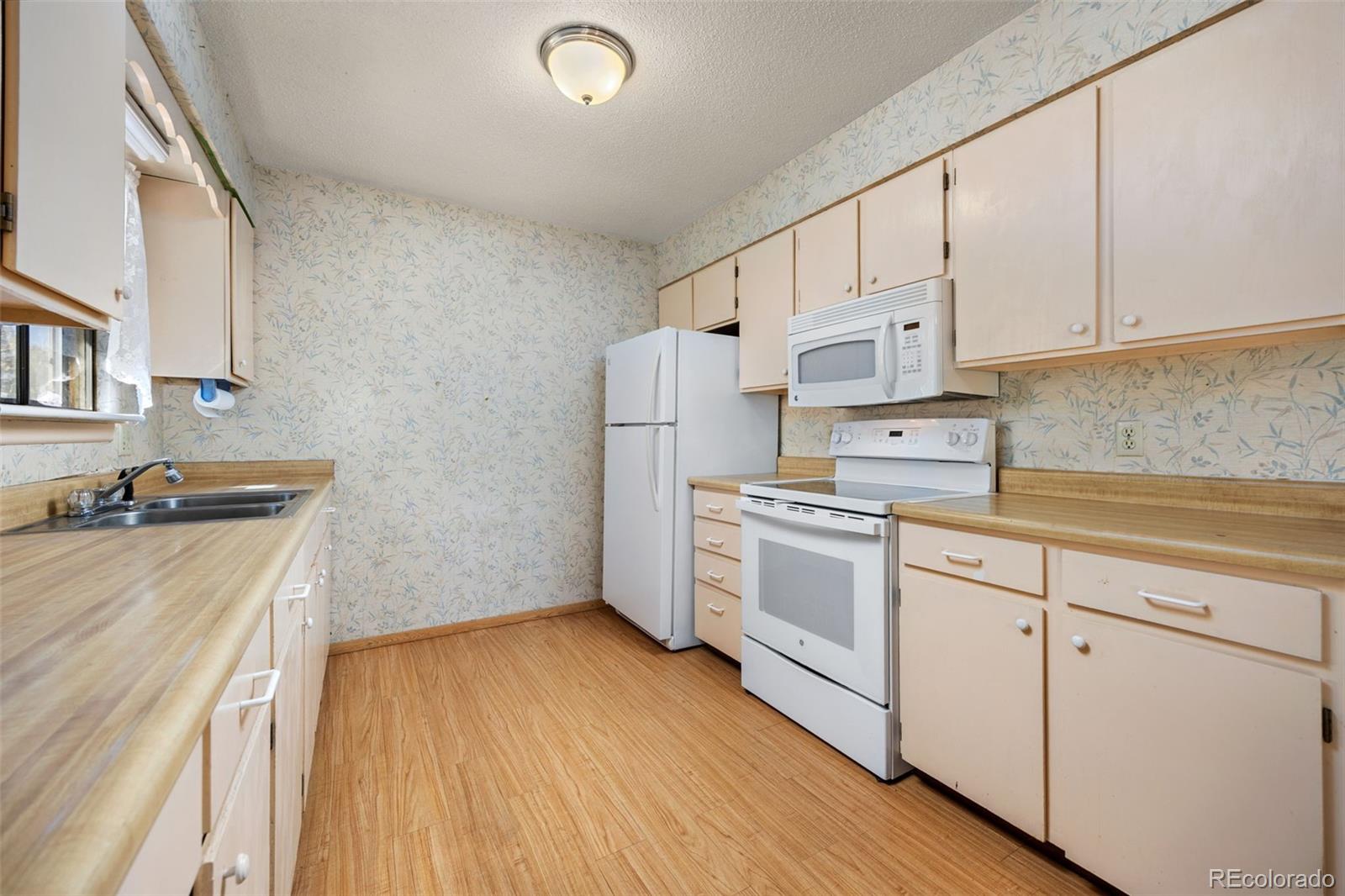 1006 Shortline Drive Fort Lupton, CO 80621 - Photo 11 of 33 a kitchen with cabinets wooden floor and stainless steel appliances