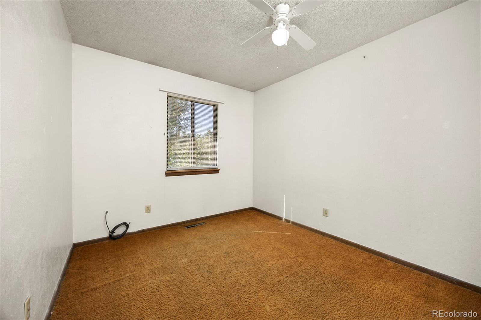 1006 Shortline Drive Fort Lupton, CO 80621 - Photo 14 of 33 an empty room with a chandelier fan and windows
