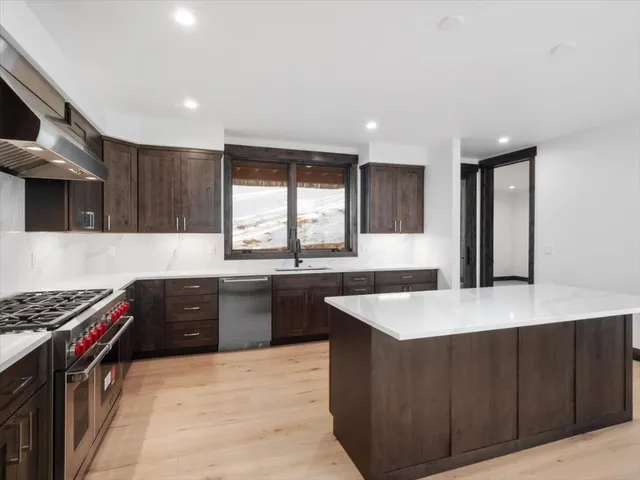a kitchen with granite countertop a stove a sink and a refrigerator
