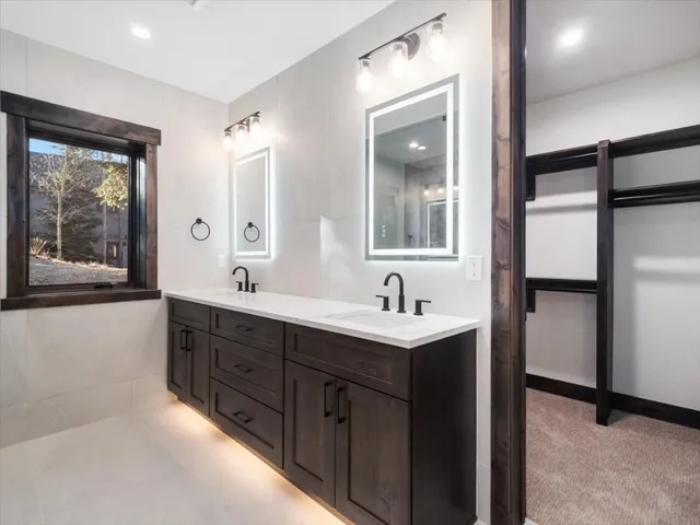 a bathroom with a double vanity sink and mirror with window