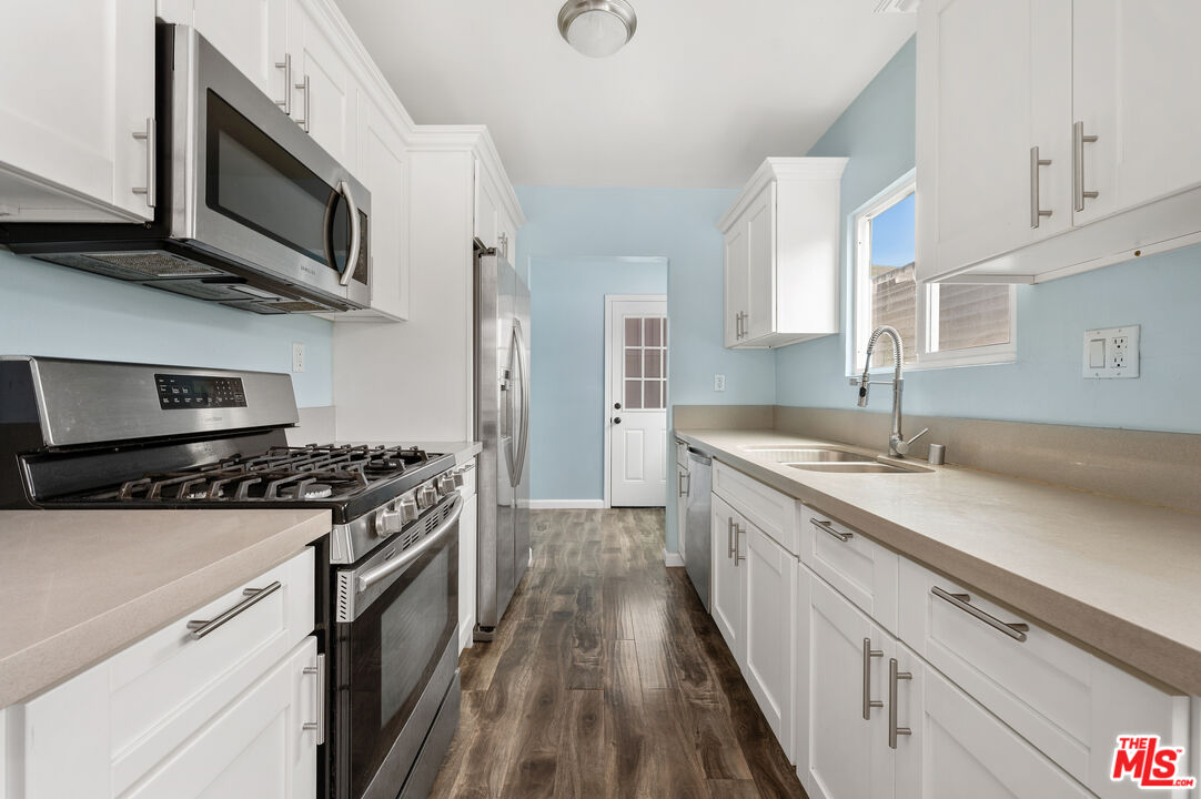 2738 Cloverdale Avenue Los Angeles, CA 90016 - Photo 12 of 17 a kitchen with stainless steel appliances a sink dishwasher stove and microwave with wooden floor