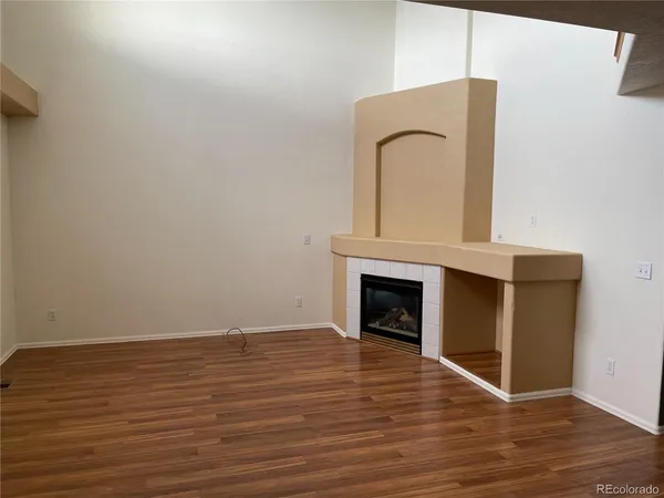a view of empty room with wooden floor and fireplace