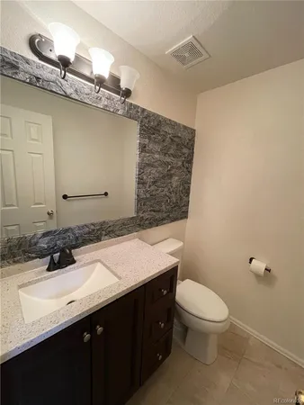 a bathroom with a granite countertop sink a toilet and mirror